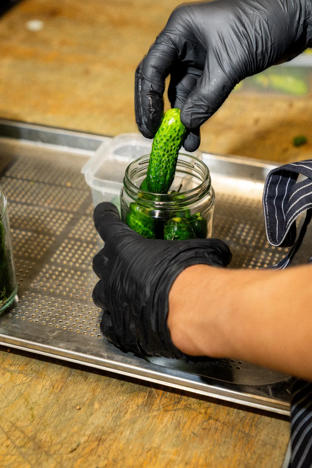 Eine Gurke wird während der Produktion von Hand ins Glas gefüllt